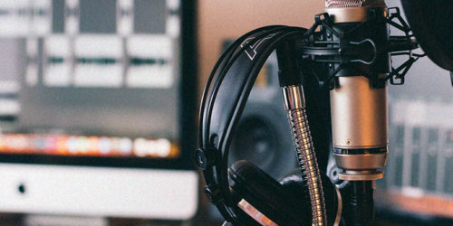 Podcasting equipment. A pair of headphones hanging on a studio microphone. | Readable, the ultimate readability tool for proofreading and writing