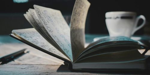 Journal on a desk with cup behind,